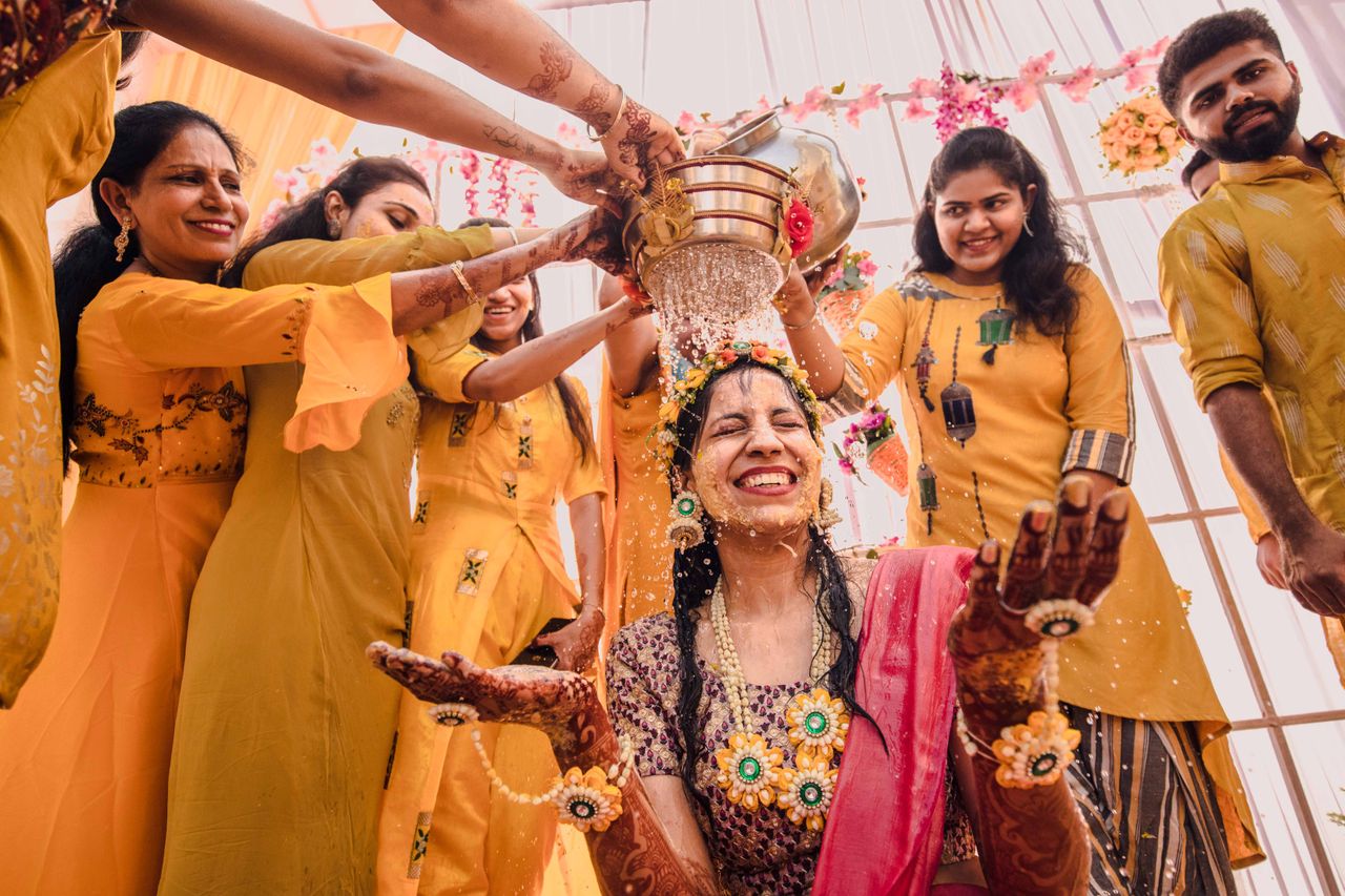 A vibrant traditional ceremony featuring smiling people in colorful attire, cheerfully pouring water.