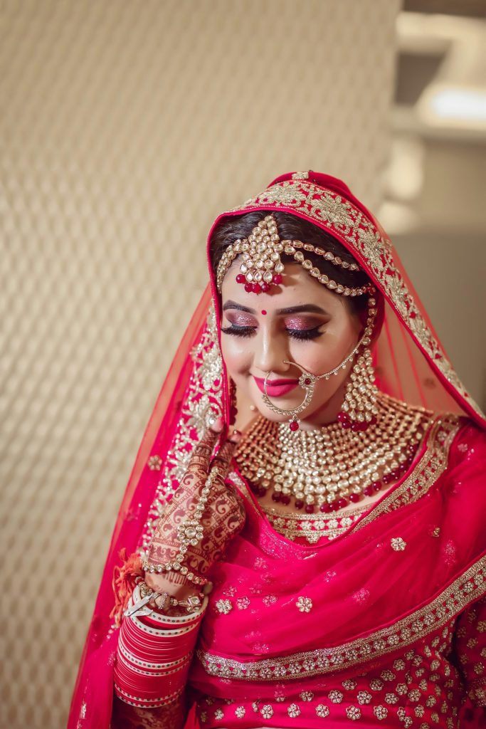 Bride in a red bridal outfit with gold jewellery and henna on her hands