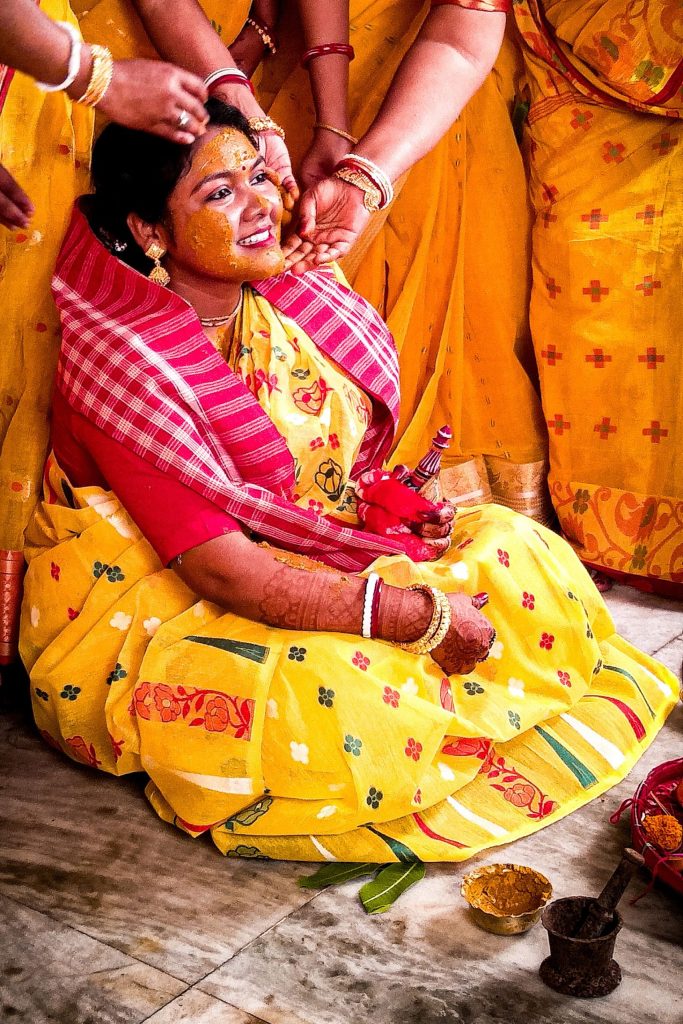 Bride in a yellow saree during a joyful holud ceremony