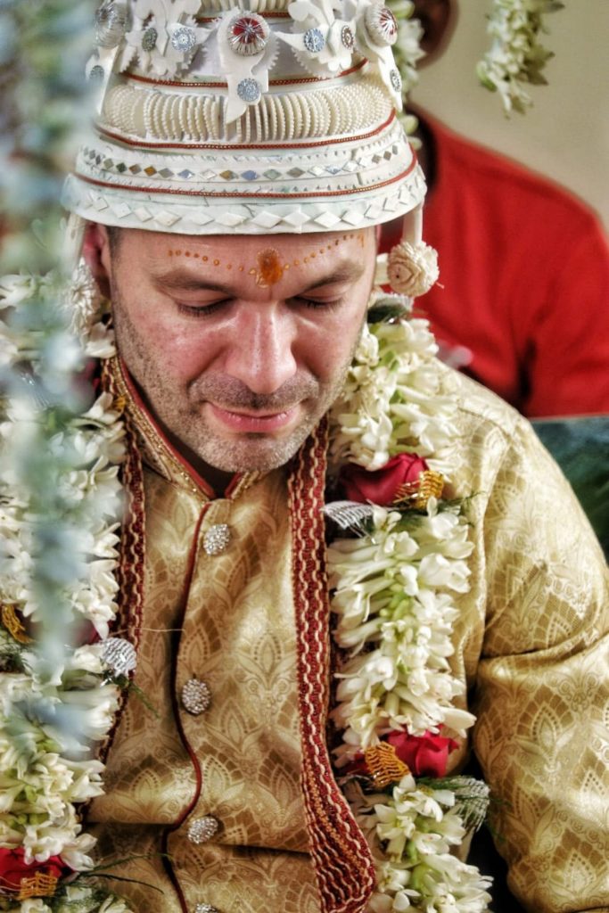 Groom in traditional attire wearing flower garlands