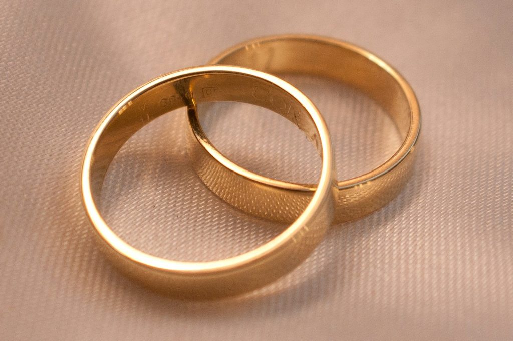 Two interlocking gold wedding bands on cream fabric
