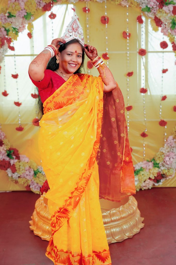 Woman in a yellow sari posing at a holud celebration